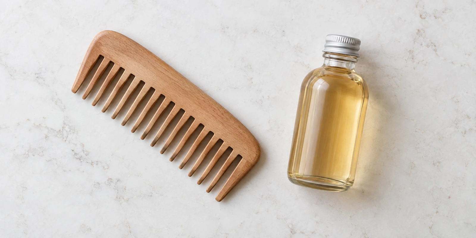 Wide-tooth comb and small bottle of diluted apple cider vinegar representing the viral vinegar comb hair trend